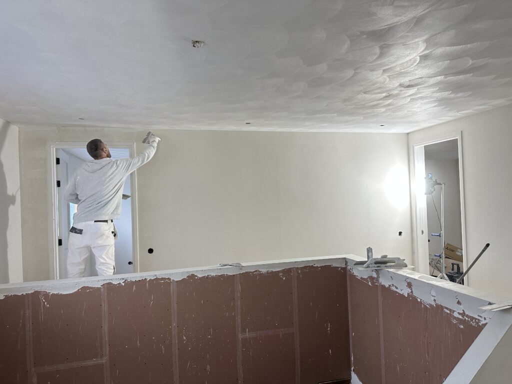 Stukadoor werkt een wand af in een afgeplakte ruimte