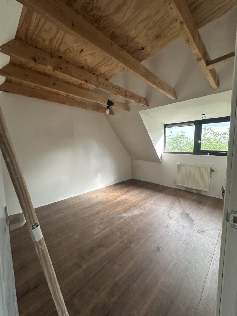 Zolderkamer met strak gestucte wanden onder houten kap